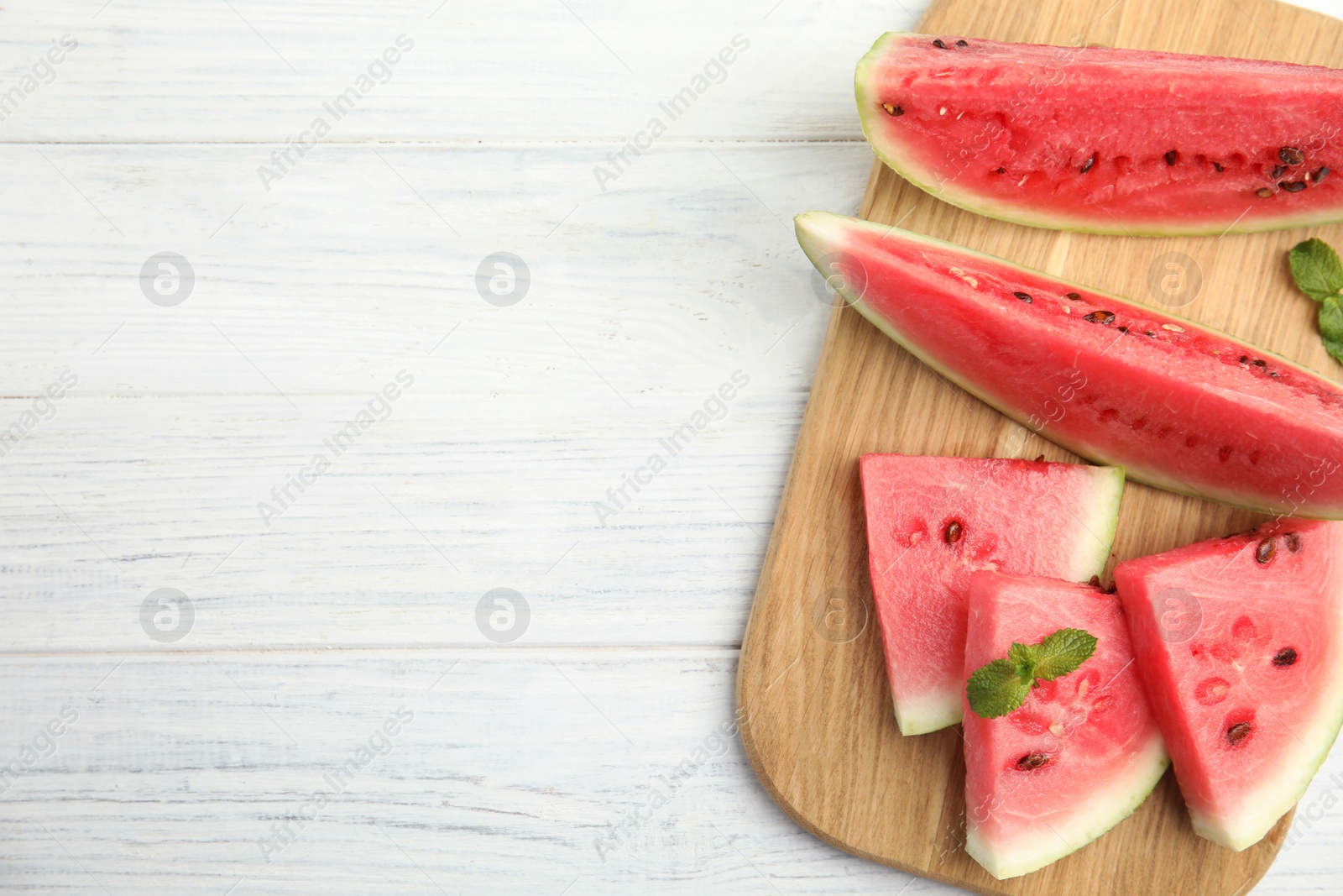 Photo of Tasty ripe cut watermelon on white wooden table, top view. Space for text