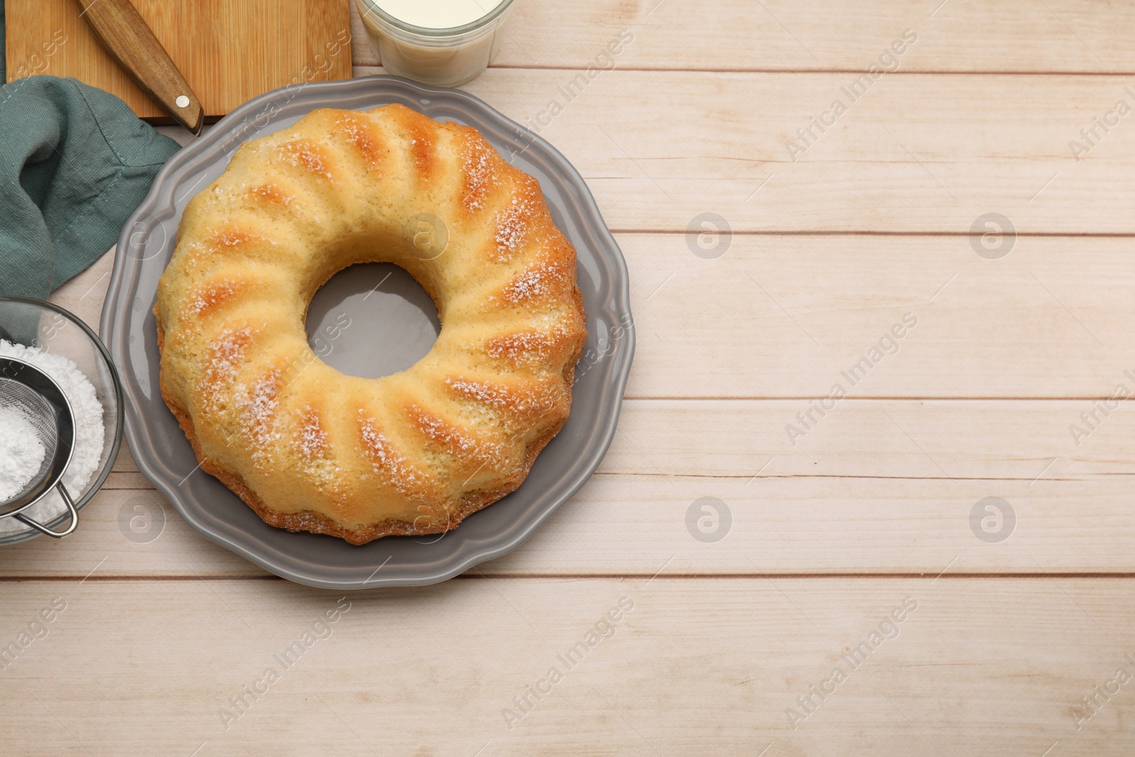 Photo of Delicious sponge cake with powdered sugar on wooden table, flat lay. Space for text