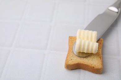 Photo of Tasty butter curl, knife and piece of dry bread on white tiled table, closeup. Space for text