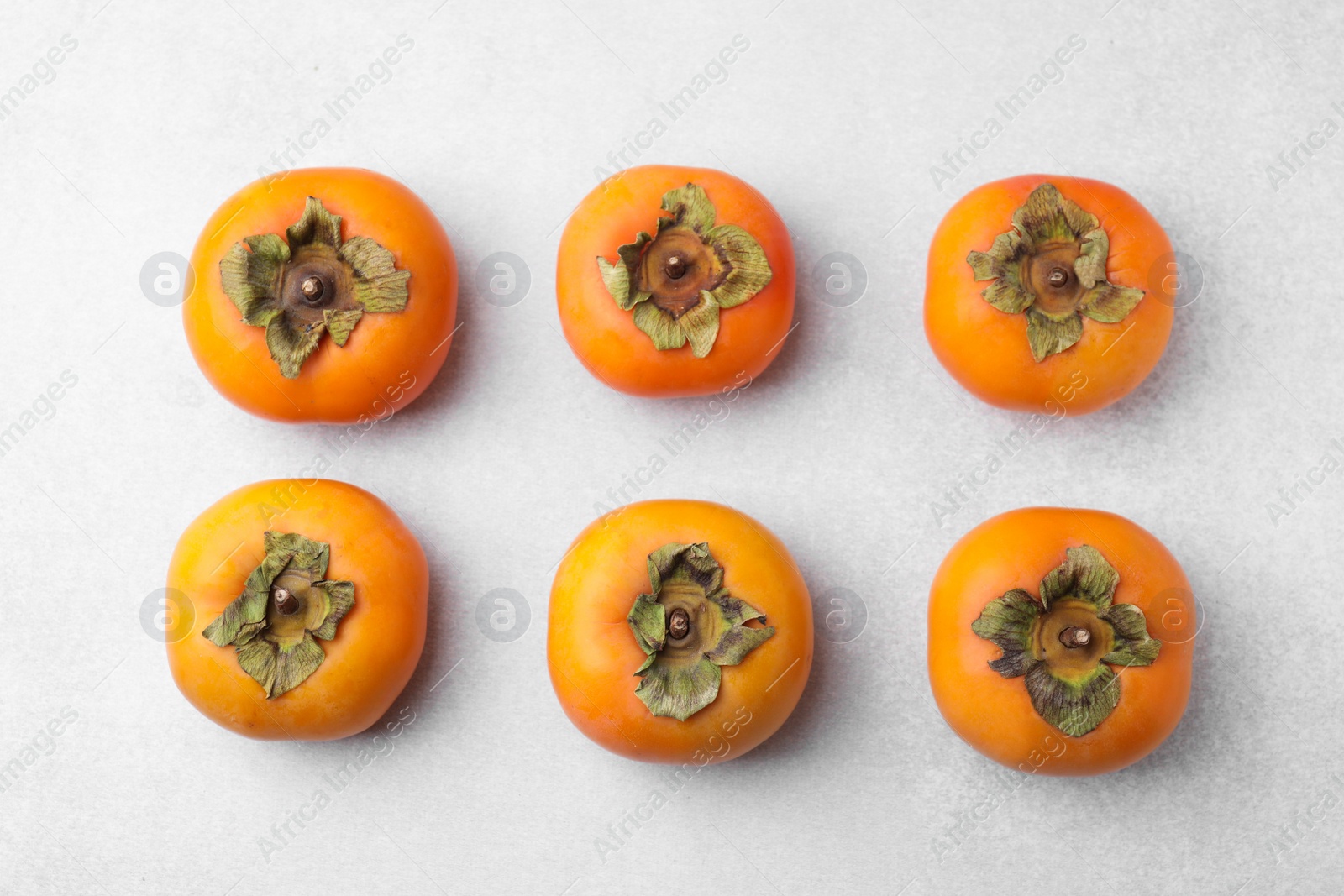 Photo of Delicious ripe juicy persimmons on light table, flat lay