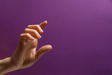 Photo of Woman holding something in hand on purple background, closeup. Space for text