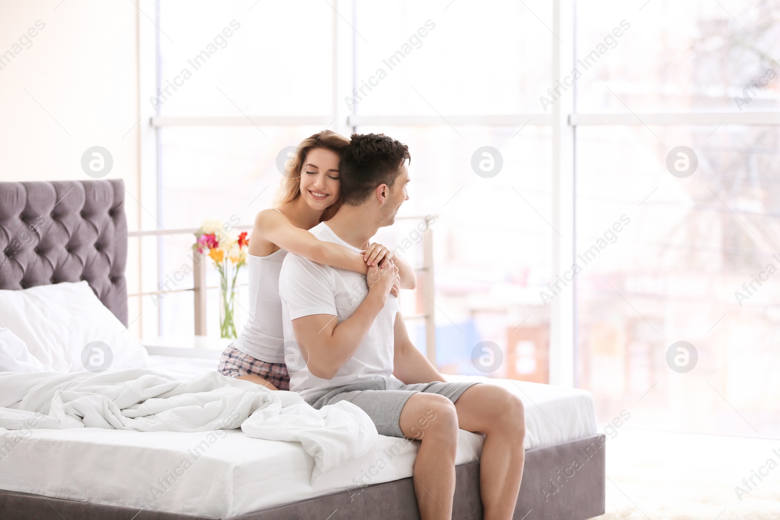 Photo of Young couple hugging on bed at home