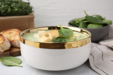 Delicious spinach cream soup with croutons in bowl on white table