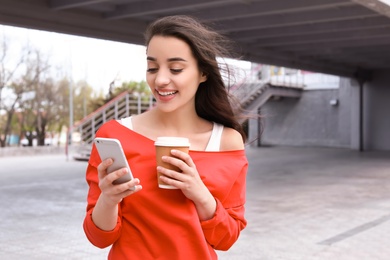 Photo of Young woman using mobile phone outdoors