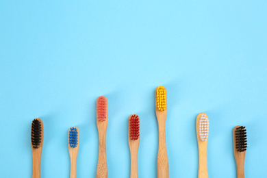 Photo of Toothbrushes made of bamboo on light blue background, flat lay. Space for text