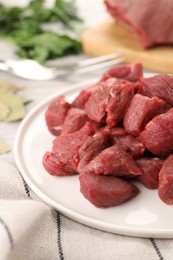 Photo of Plate with pieces of raw beef meat on table, closeup