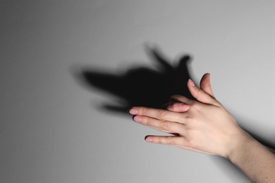 Photo of Shadow puppet. Woman making hand gesture like dog on grey background, closeup