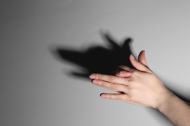 Shadow puppet. Woman making hand gesture like dog on grey background, closeup