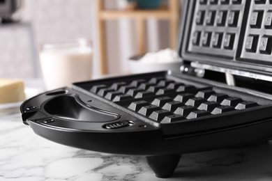 Modern Belgian waffle maker on white marble table, closeup