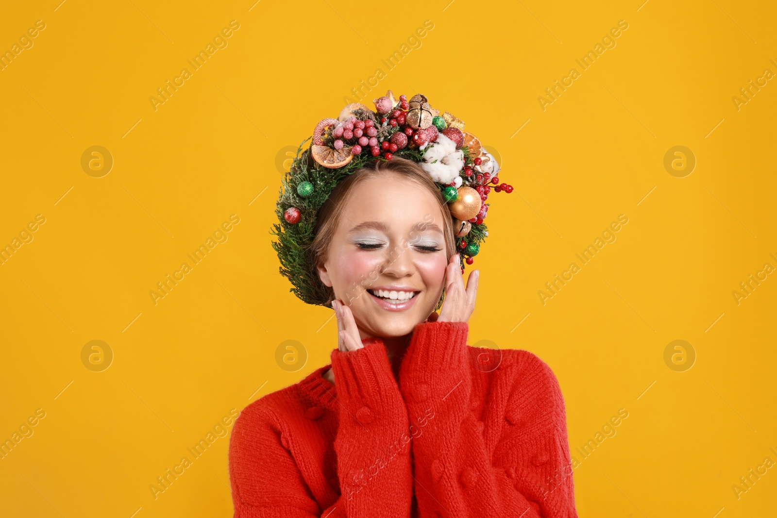 Photo of Beautiful young woman wearing Christmas wreath on yellow background