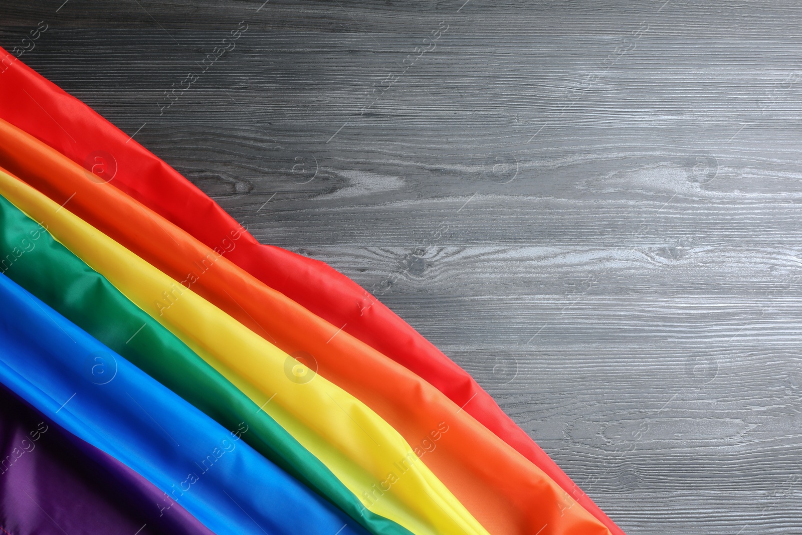 Photo of Bright rainbow gay flag on wooden background, top view with space for text. LGBT community