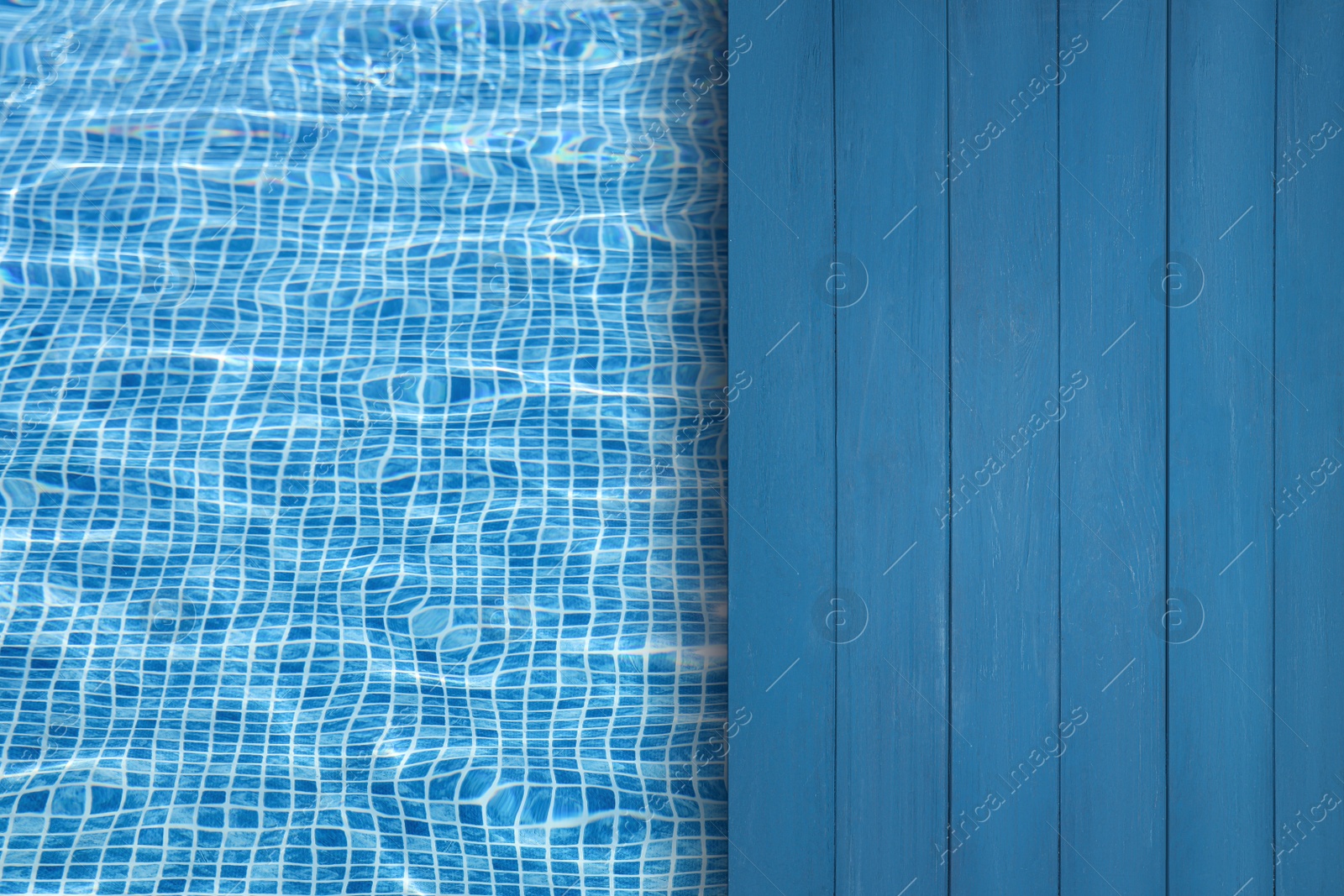 Image of Empty blue wooden surface near swimming pool with clear water. Space for design