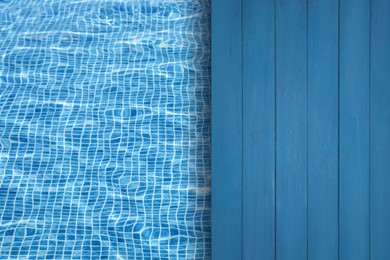 Image of Empty blue wooden surface near swimming pool with clear water. Space for design