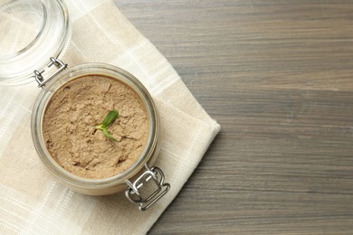 Glass jar with delicious liver pate on wooden table, top view. Space for text