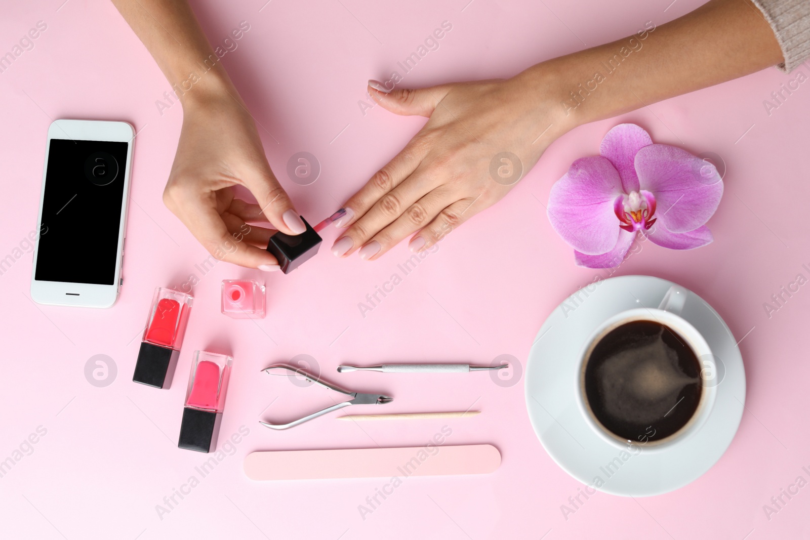 Photo of Woman applying nail polish on color background, above view