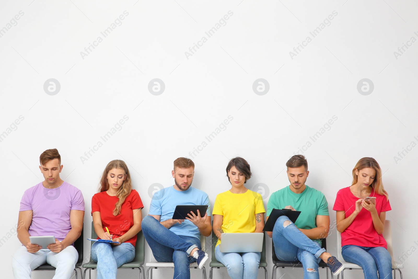 Photo of Group of young people waiting for job interview near light wall