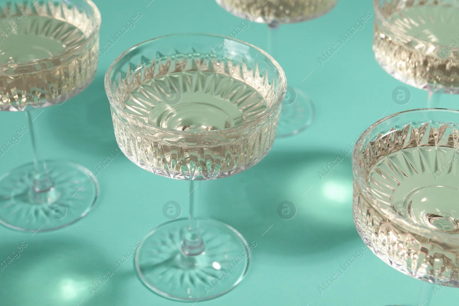 Photo of Glasses of expensive white wine on turquoise background