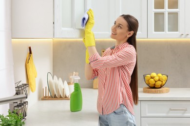 Spring cleaning. Young woman tidying up kitchen at home
