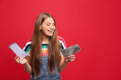 Photo of Portrait of happy young woman with lottery ticket and money on red background