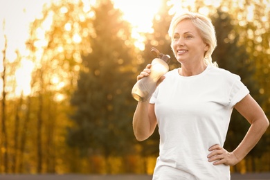 Photo of Sporty mature woman with bottle of water outdoors
