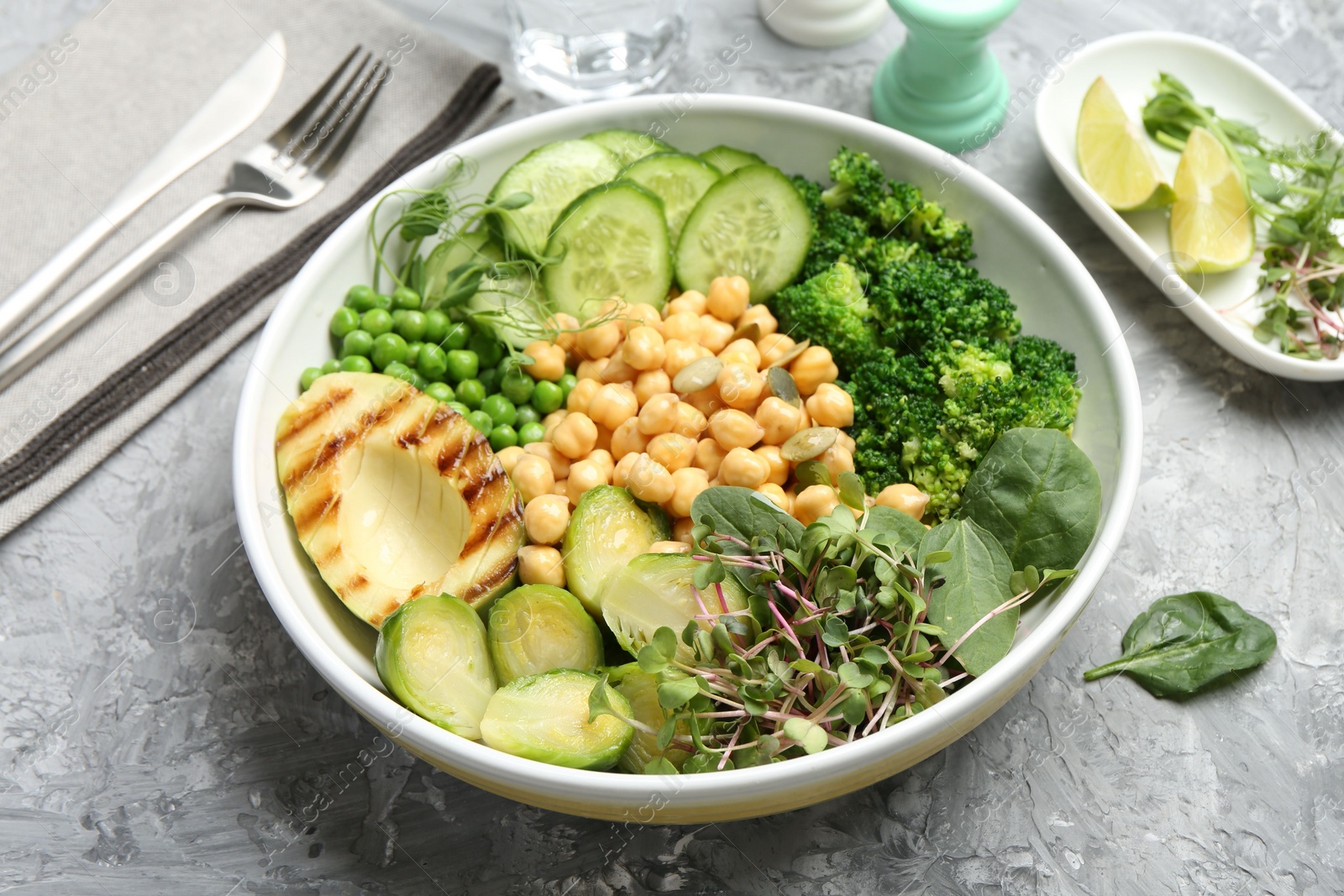 Photo of Healthy meal. Tasty vegetables and chickpeas in bowl on grey table