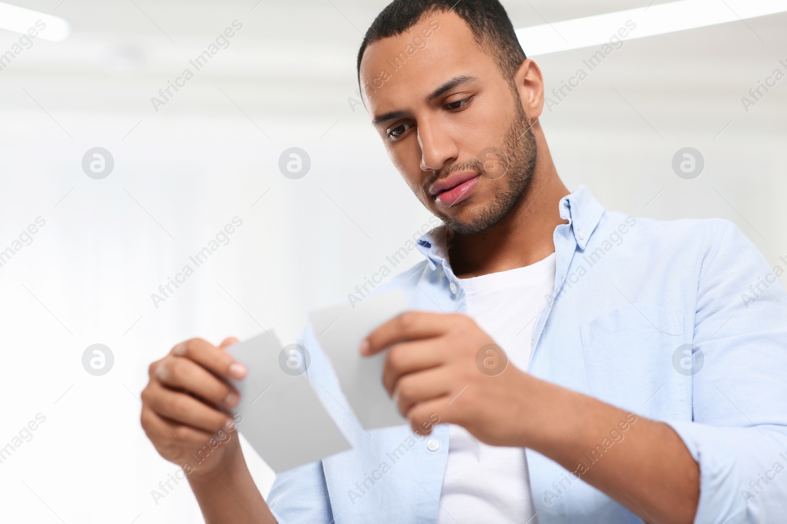 Photo of Upset African American man with torn photo indoors Divorce concept