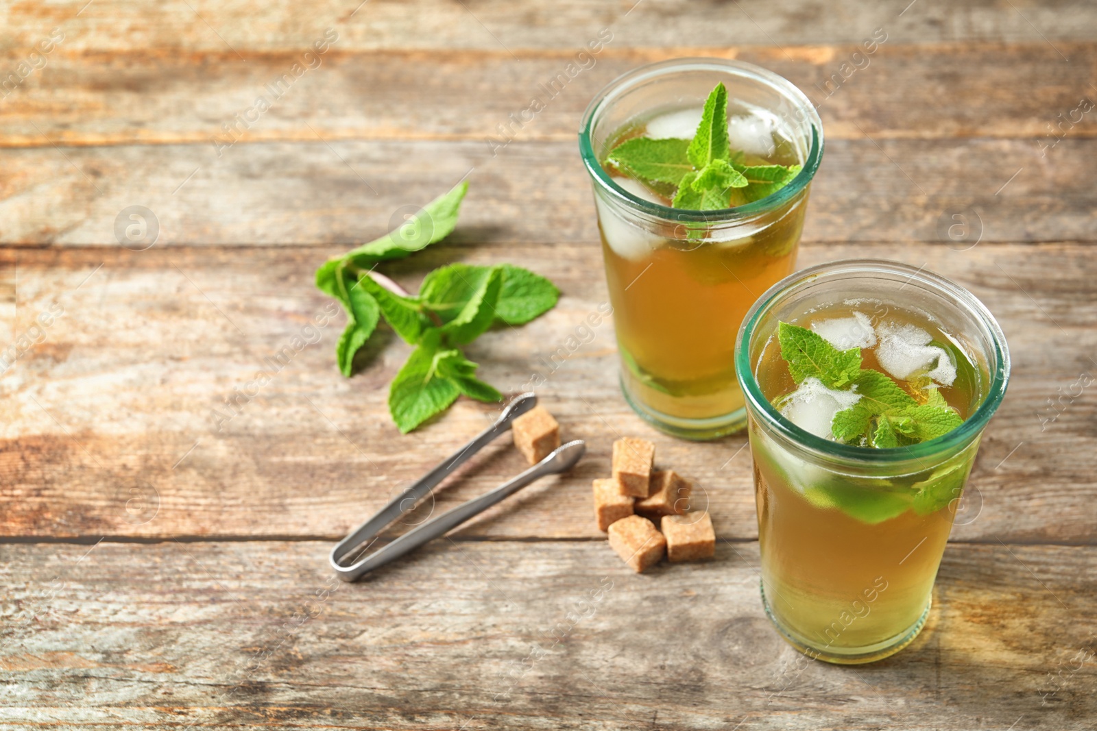 Photo of Glasses with aromatic mint tea, fresh leaves and sugar cubes on wooden table