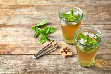 Photo of Glasses with aromatic mint tea, fresh leaves and sugar cubes on wooden table