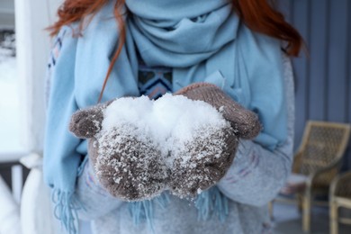 Photo of Woman holding snow in wooden gazebo outdoors, closeup. Winter vacation