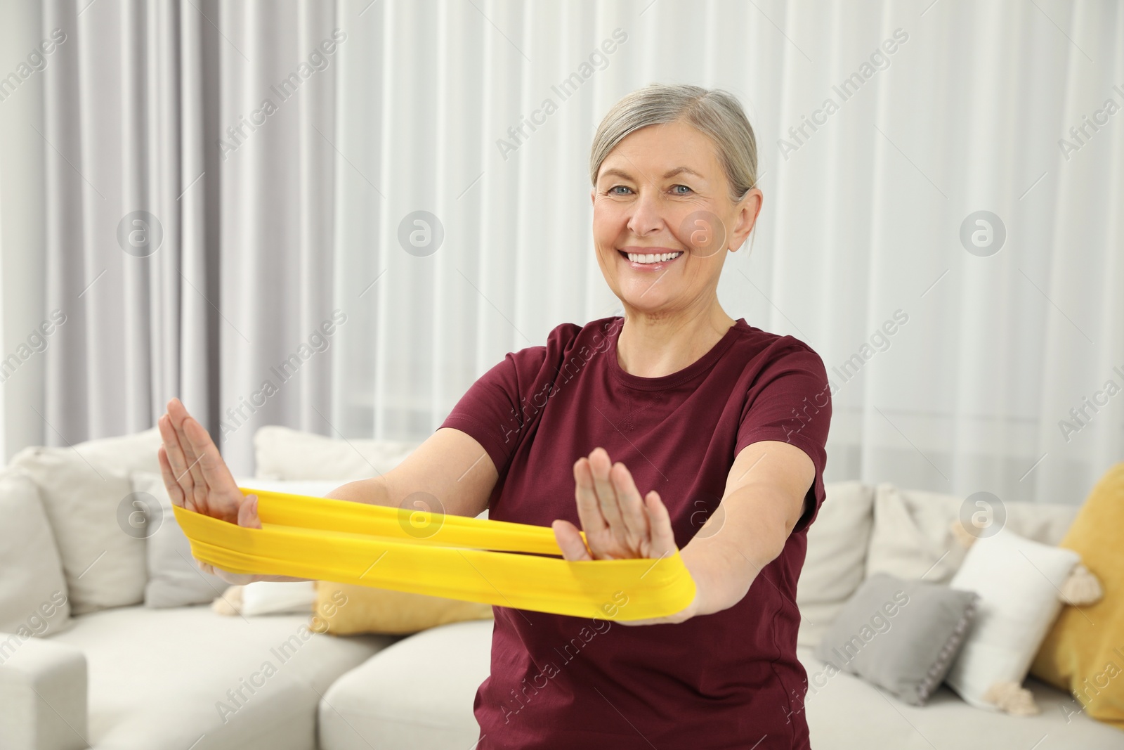 Photo of Senior woman doing exercise with fitness elastic band at home