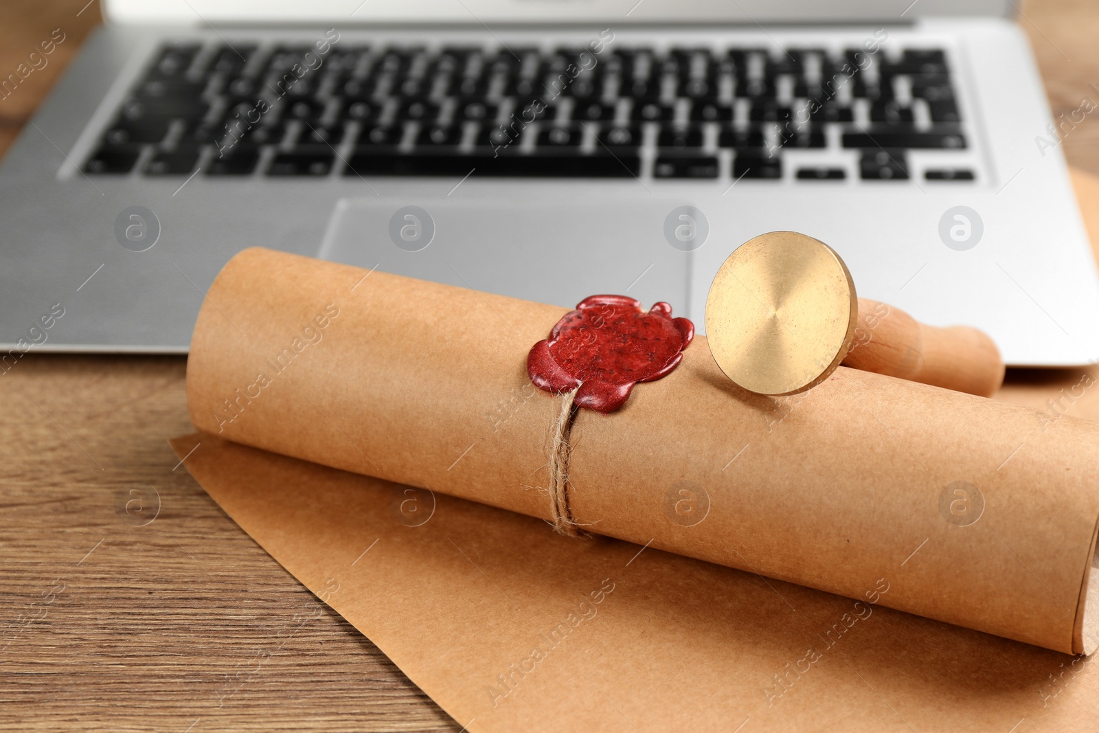 Photo of Notary's public pen and sealed document near laptop on wooden table