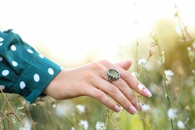 Photo of Young woman wearing beautiful silver ring with prehnite gemstone outdoors, closeup
