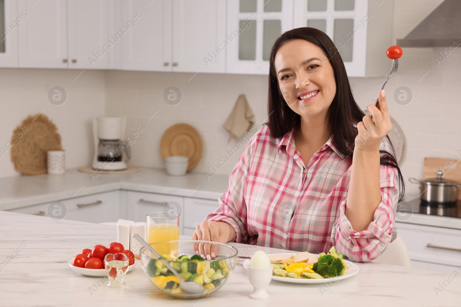 Photo of Beautiful overweight woman having healthy meal at table in kitchen