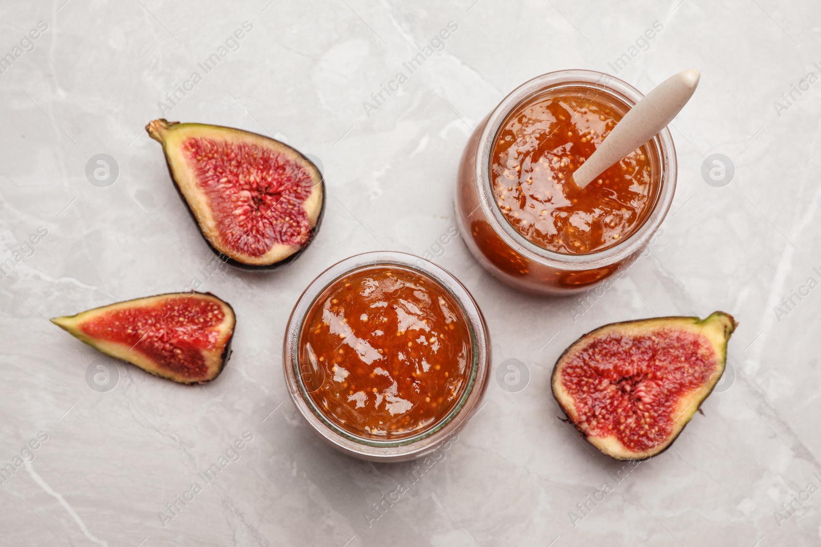 Photo of Homemade delicious fig jam on marble table, flat lay