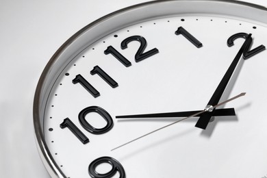 Stylish round clock on white background, closeup. Interior element