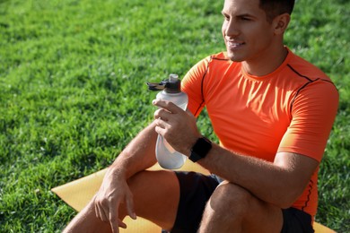 Photo of Man with fitness tracker and bottle of water after training in park