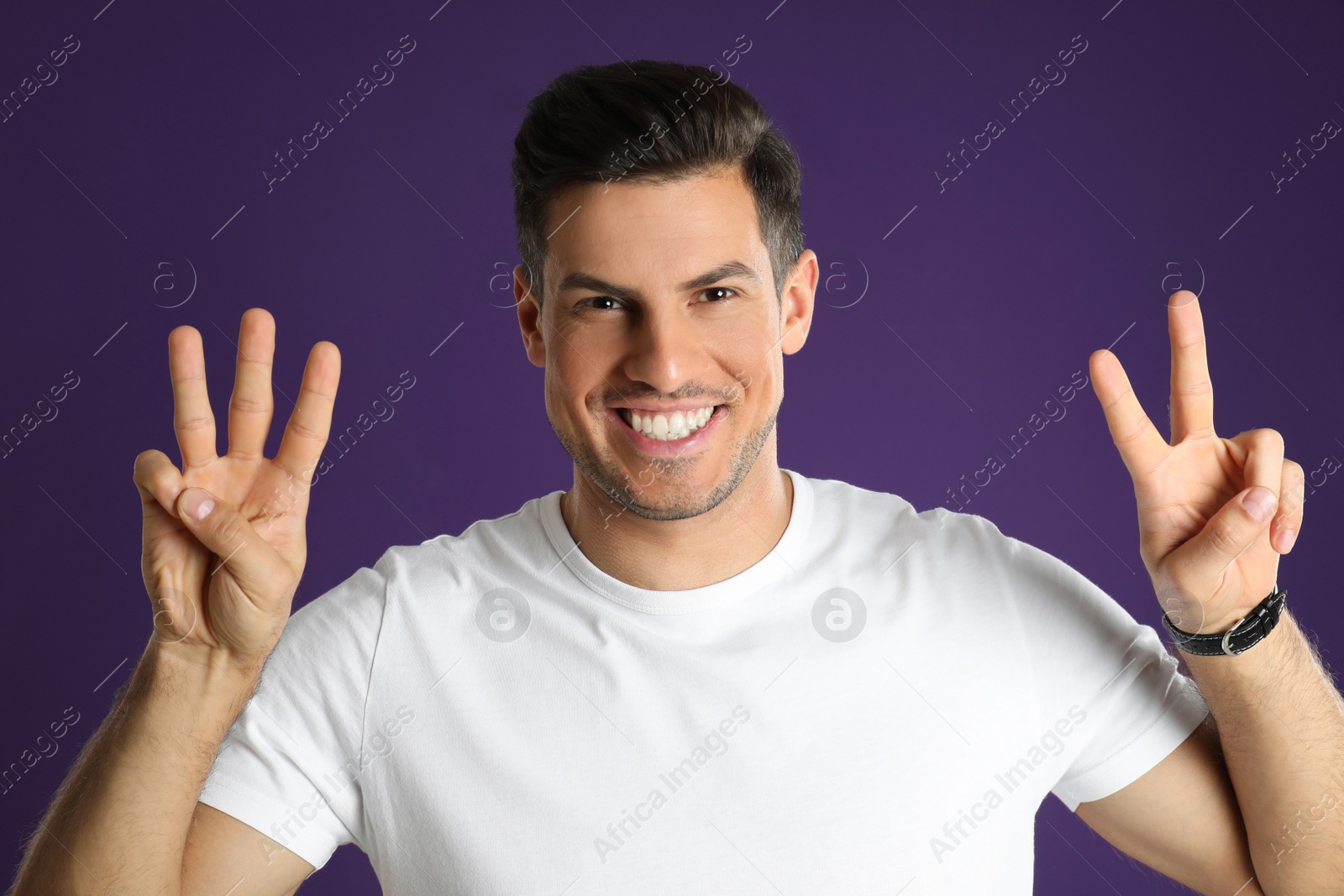 Photo of Man showing number five with his hands on purple background