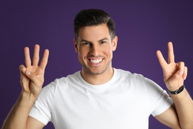 Photo of Man showing number five with his hands on purple background