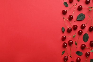 Photo of Tasty ripe cherries with leaves on red background, flat lay. Space for text