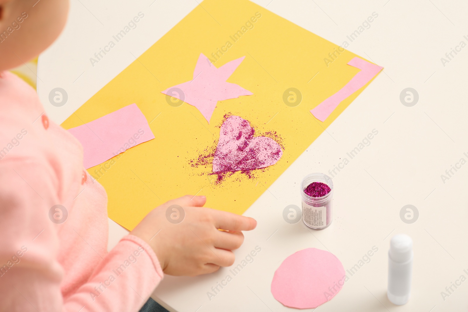 Photo of Girl with colorful paper card at desk in room, closeup. Home workplace