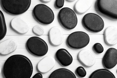 Photo of Different spa stones on white wooden table, flat lay