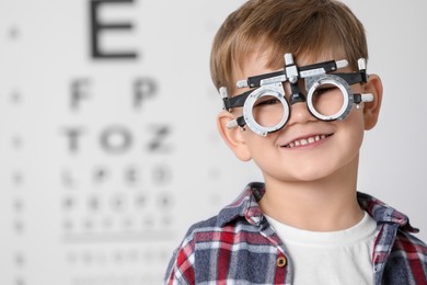 Photo of Little boy with trial frame against vision test chart