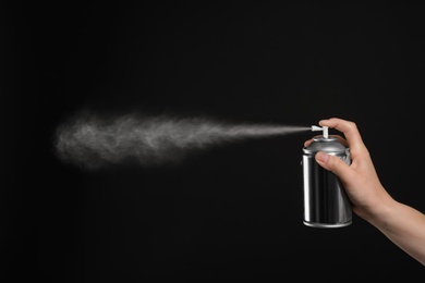 Woman spraying air freshener on black background, closeup