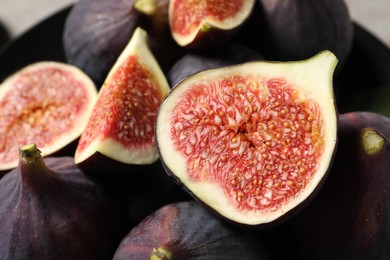 Whole and cut ripe figs on blurred background, closeup