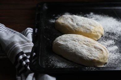 Photo of Raw dough for ciabatta and flour on wooden table