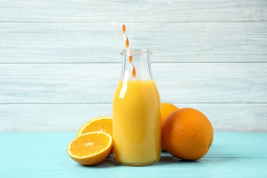 Bottle of orange juice and fresh fruits on light blue wooden table