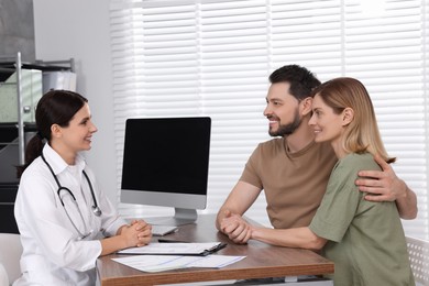 Photo of Couple having appointment with fertility doctor in clinic. Patient consultation