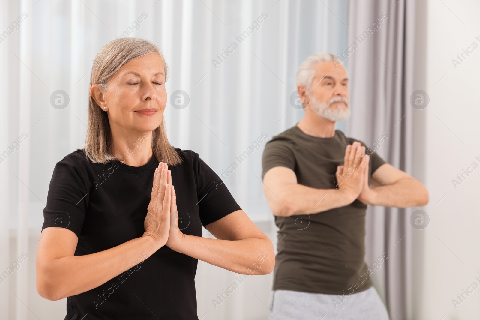 Photo of Senior couple practicing yoga at home, selective focus