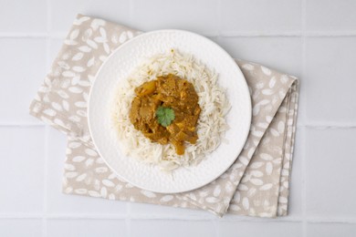 Photo of Delicious chicken curry with rice on white tiled table, top view