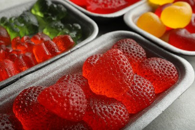 Different delicious gummy candies on grey table, closeup